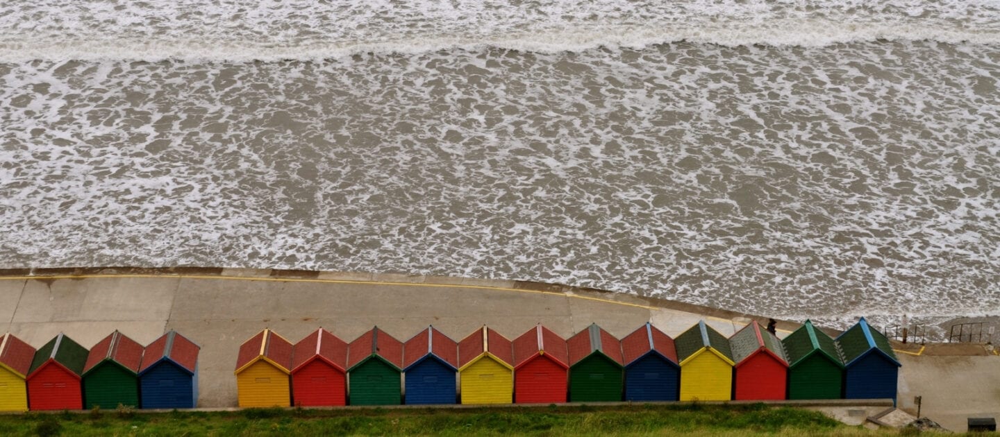 Beach huts with foamy surf on Whitby beach