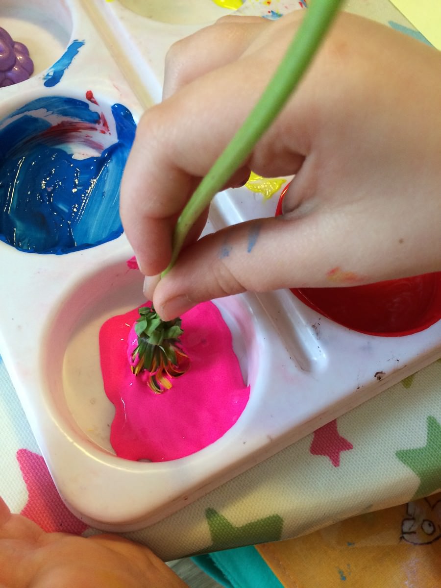 How to paint with flowers. Childs hand using a flower as a paint brush